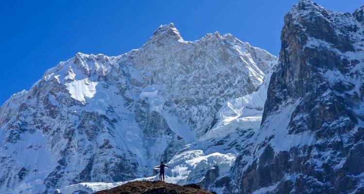 Eenzame trekker met uitgestrekte armen voor imposante sneeuwbedekte Himalaya-pieken.