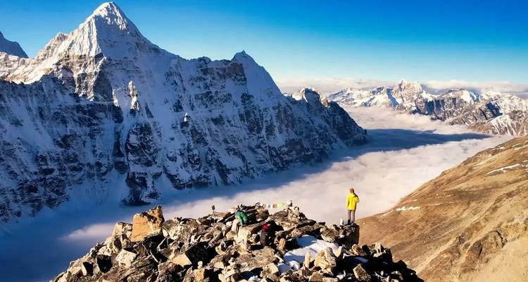 Hoog uitzichtpunt boven de besneeuwde, ruige Himalaya boven een zee van wolken met een trekker.