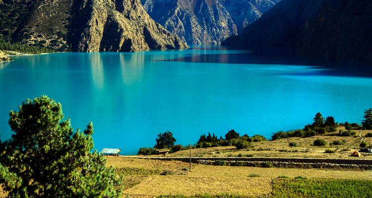 Briljant turquoise alpenmeer omlijst door steile rotsachtige kliffen en beboste hellingen.