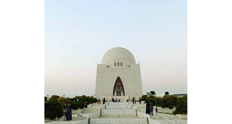 Front view of the white marble Mazar-e-Quaid mausoleum with visitors on wide steps