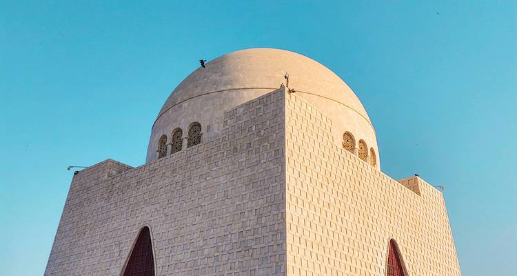 Low-angle shot of the domed white marble mausoleum against a clear blue sky