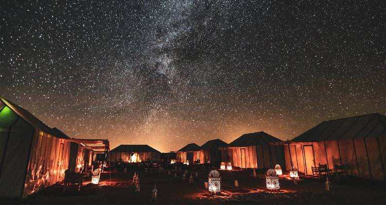 Campamento de lujo en el desierto iluminado por faroles bajo un deslumbrante cielo del Sahara lleno de estrellas