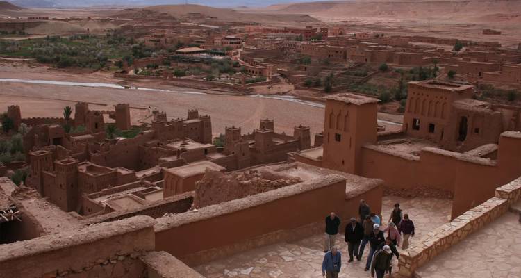 Los turistas caminan por las murallas de adobe que dominan el antiguo ksar de Ait Benhaddou y su valle fluvial