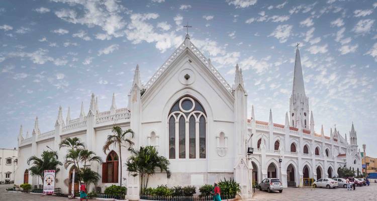 La basilique Santhome néo-gothique d'un blanc éclatant se dresse contre un ciel parsemé de petits nuages, des palmiers encadrant sa façade.
