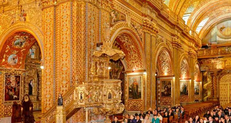 Üppig vergoldeter Innenraum der Kirche La Compañía de Jesús in Quito voller sitzender Besucher