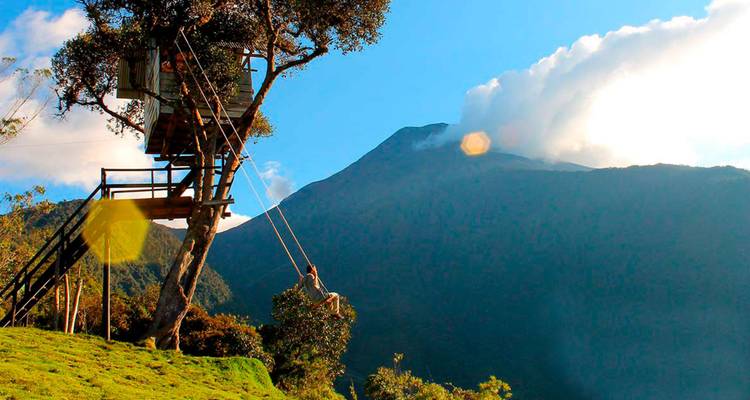 Abenteurer auf der berühmten Schaukel bei Casa del Árbol mit dem Vulkan Tungurahua, der im Hintergrund unter der Morgensonne aufragt