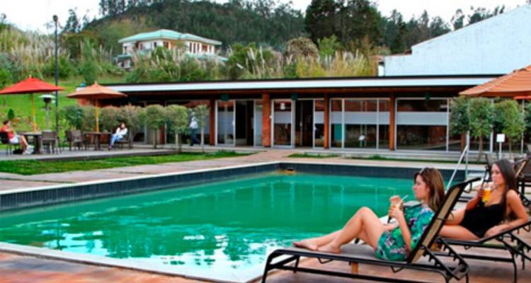 Niedrig aufgelöstes Foto von zwei Frauen, die neben einem rechteckigen Außenpool in einem Resort entspannen