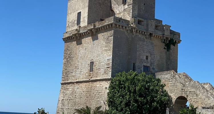 Une tour de guet côtière historique se dresse contre un ciel méditerranéen bleu et dégagé.