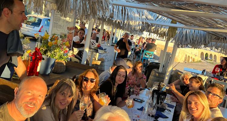 Des amis partagent des boissons et des rires dans un restaurant en bord de mer pendant l'heure dorée.