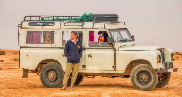Un Land Rover clásico con pasajeros observa a través de la llanura desértica marroquí.