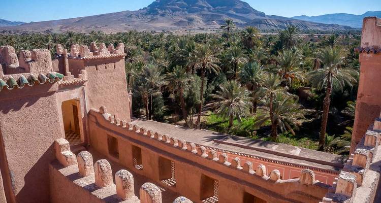 Vista desde la azotea de una kasbah sobre un exuberante oasis de palmeras y montañas en el sur de Marruecos.