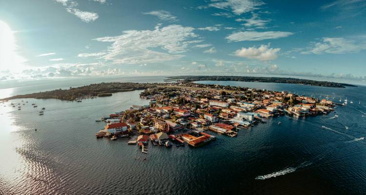 Aerial panorama of a colorful island town surrounded by calm lake waters beneath a bright blue sky