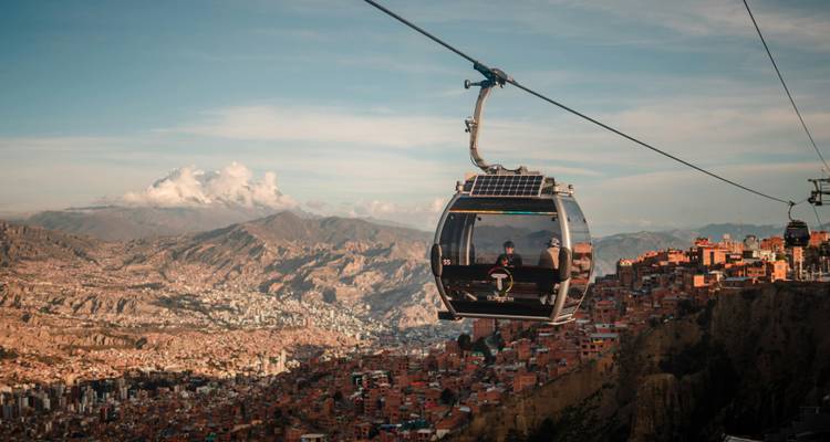 Gondole moderne de téléphérique glissant au-dessus de la ville tentaculaire de La Paz avec les sommets accidentés des Andes au loin