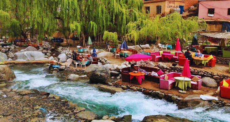 Les cafés colorés au bord de la rivière, avec leurs parasols éclatants et leurs coussins, sont situés à côté d'un cours d'eau limpide à débit rapide, sous des saules pleureurs.