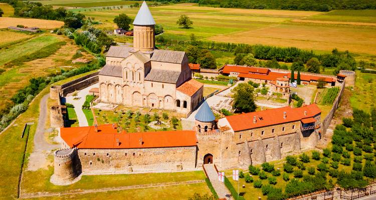 Vista aérea del complejo de la Catedral de Alaverdi rodeado de tierras de cultivo verdes de Kakheti y huertos.
