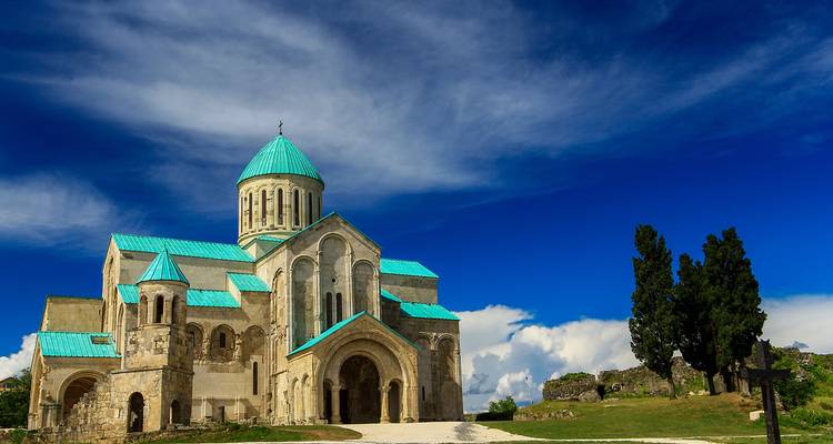 La Catedral de Bagrati con techo turquesa corona una colina cubierta de hierba bajo los vívidos cielos azules de Kutaisi.