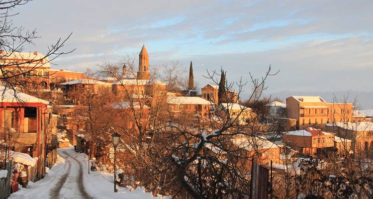Los tejados espolvoreados de nieve y el campanario de la iglesia del pueblo en la colina de Sighnaghi brillan bajo la suave luz invernal.