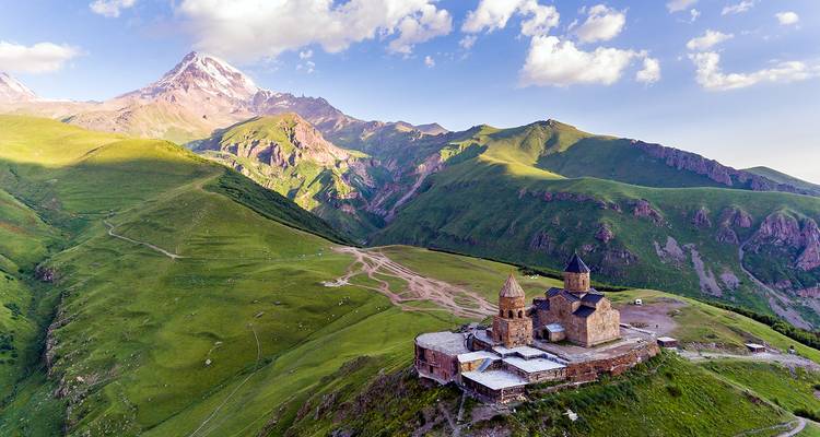 L'église de la Trinité de Gergeti se dresse sur une crête sous le mont Kazbek enneigé au milieu du paysage grandiose des montagnes du Caucase.
