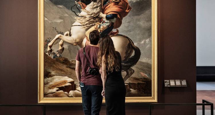 Couple admires a dramatic historical painting inside a modern gallery space.