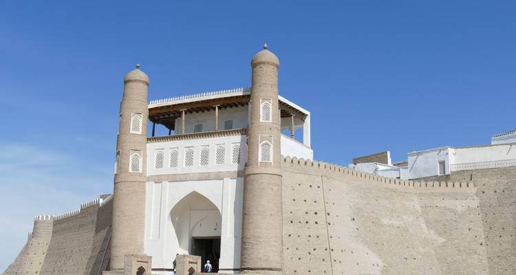 Imposante porte de forteresse en argile avec tours jumelles s'élevant au-dessus d'une place ensoleillée