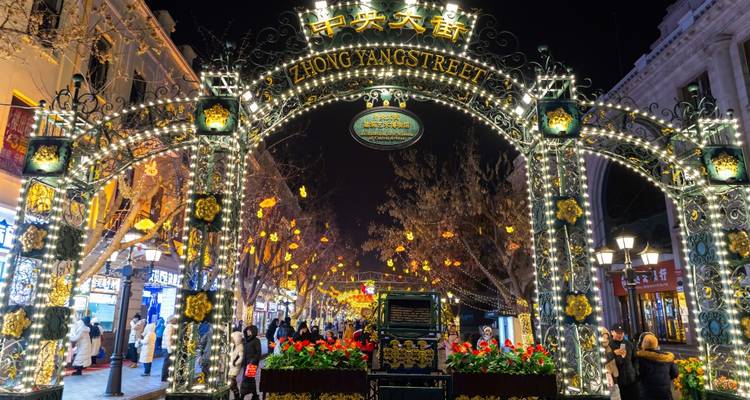 Brightly lit Zhong Yang Street archway adorned with lanterns and crowds at night.