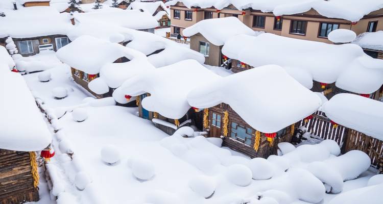 Charming village rooftops covered by deep, untouched snow seen from above.