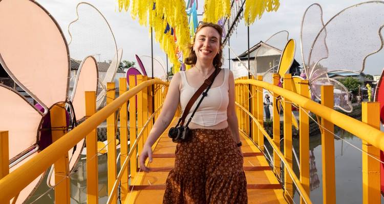 Happy traveler walks across a bright yellow footbridge decorated with giant butterfly panels.