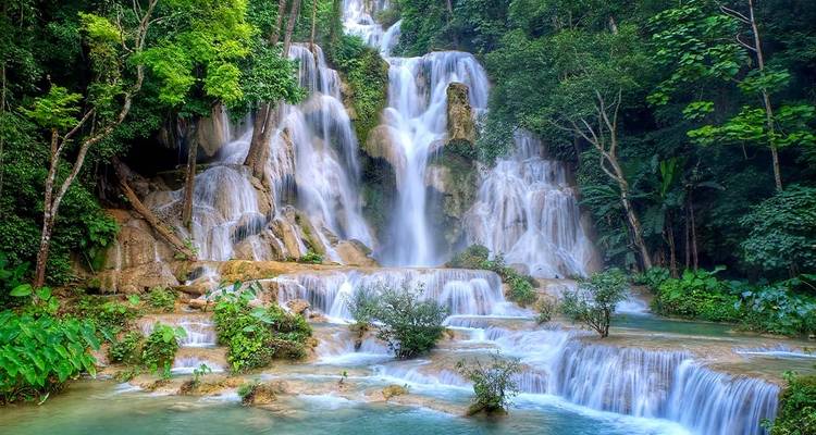 The multi-tiered Kuang Si Waterfall cascades through green jungle into turquoise pools.