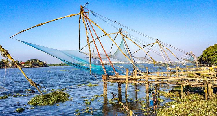 Redes de pesca tradicionales chinas extendiéndose sobre el agua en un muelle de madera en Kochi.