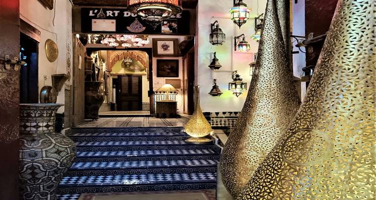 Intérieur décoratif d'une boutique d'artisan marocain avec des escaliers en mosaïque et des lampes en métal ornées.