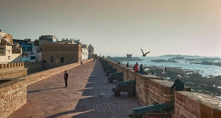 Remparts historiques en bord de mer bordés de vieux canons surplombant la côte atlantique rocheuse au coucher du soleil.