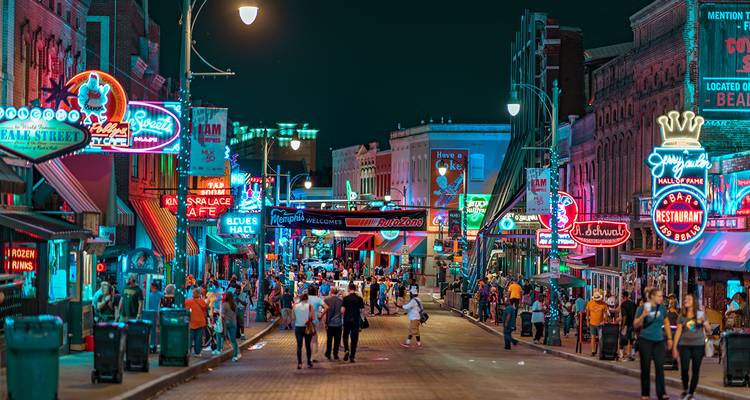 Escena de vida nocturna vibrante en una calle iluminada por neón llena de bares y multitudes por la noche