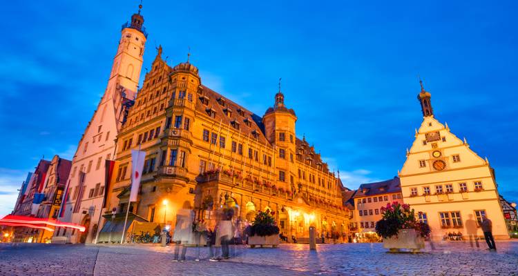 Les bâtiments historiques illuminés de la place du marché de Rothenburg brillent contre un ciel crépusculaire d'un bleu profond.