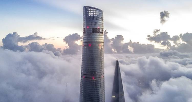 Luftaufnahme des Shanghai Tower, der bei Sonnenaufgang durch dramatische Wolken stößt.