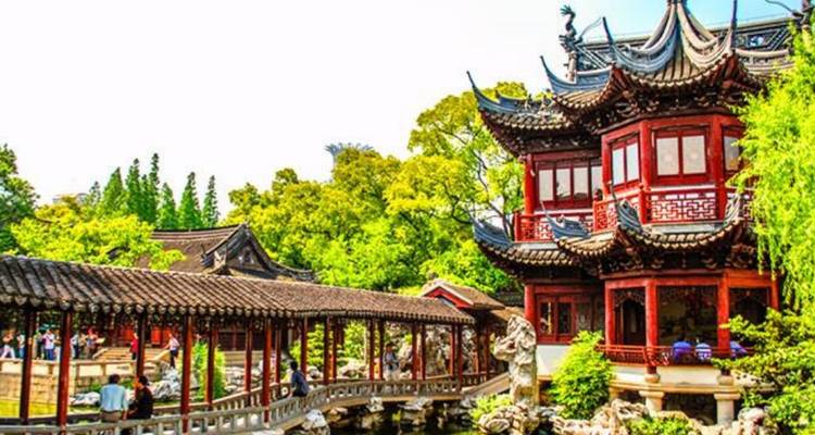 Traditionelle Pavillons und überdachte Brücke im üppigen Yu-Garten mit Besuchern, die erkunden.