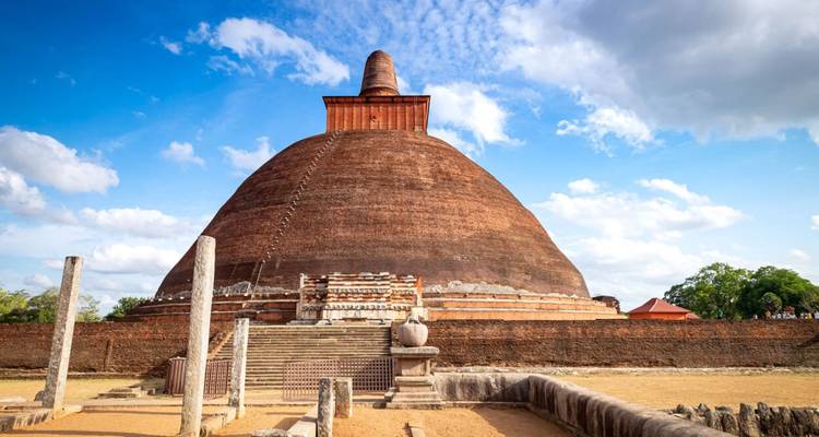 Alte rotbacksteinerne Jetavanaramaya-Stupa vor blauem Himmel mit vereinzelten Wolken.