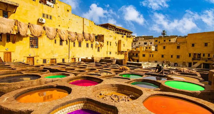 Vibrantes tinas de teñido de cuero de la Curtiduría Chouara en Fez bajo un cielo azul brillante