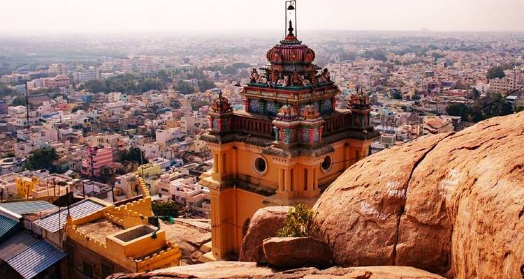 Hilltop temple pavilion overlooking a vast cityscape and rocky outcrops in hazy light.