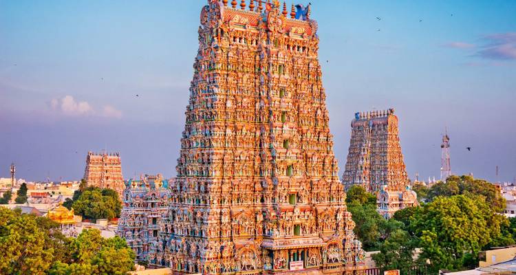 Vibrantly painted towers of Meenakshi Amman Temple rising above the cityscape in warm evening light.
