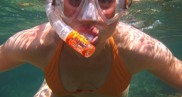 Snorkelaar met masker en oranje bikini zwemmend net onder het wateroppervlak