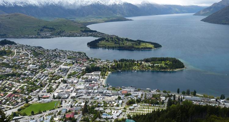 Panoramisch luchtfoto van Queenstown aan een meer omringd door groene heuvels en besneeuwde bergtoppen
