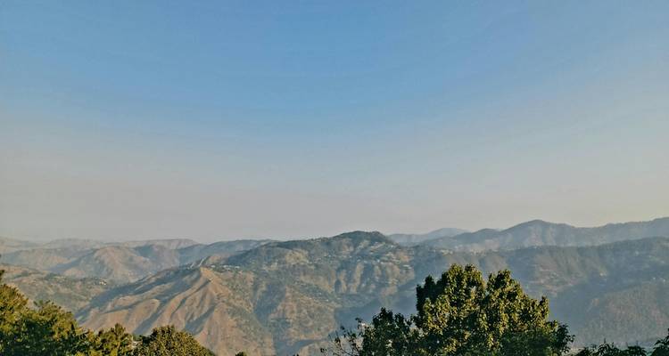 Expansive view of hazy mountain ranges and valleys under clear sky