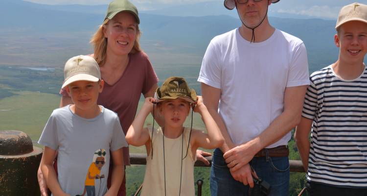 Familie posiert an einem malerischen Aussichtspunkt über dem Ngorongoro-Krater unter strahlendem Himmel