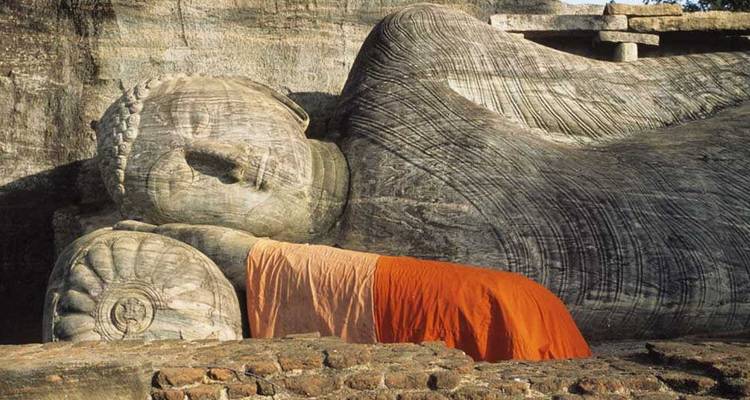Ancienne statue de Bouddha couché drapée d'une robe orange sculptée dans la pierre à Polonnaruwa