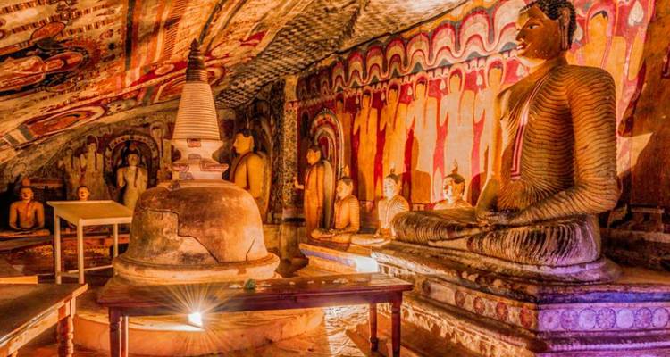 Intérieur illuminé du temple rupestre de Dambulla avec des statues de Bouddha et un stupa
