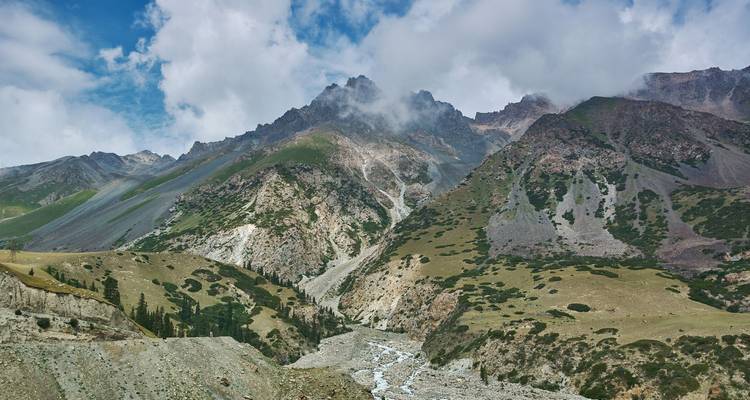 Les Rocheuses bordent une gorge abrupte où une rivière se fraie un chemin entre des versants sous un ciel partiellement nuageux.