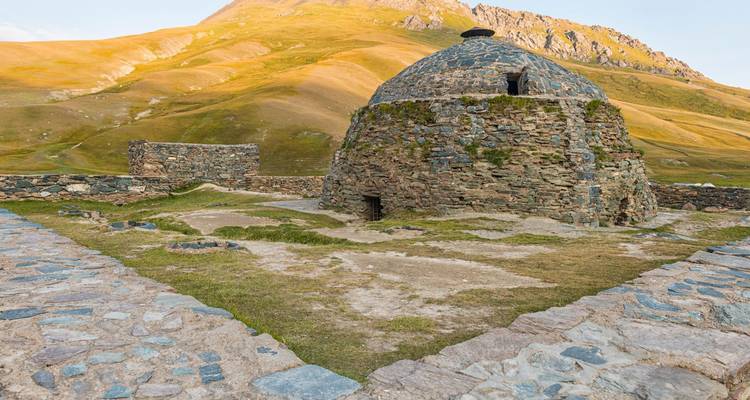 La caravansérail ancienne aux dômes de pierre de Tash Rabat se dresse solitaire au milieu de collines dorées ondulantes.