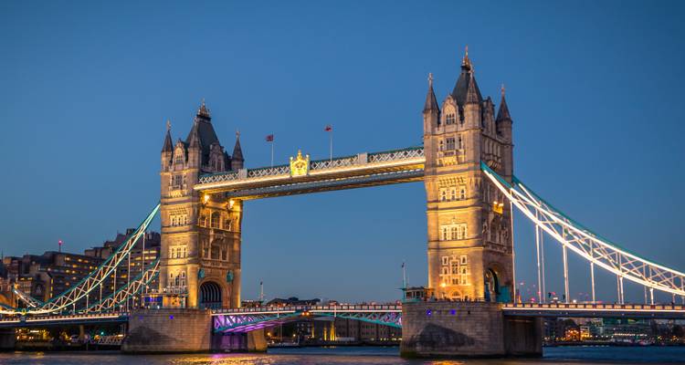 Die Tower Bridge bei Dämmerung beleuchtet und spiegelnd auf der Themse.