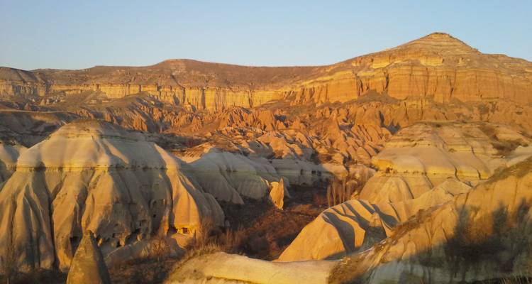 Les vagues rocheuses et les falaises aux teintes dorées brillent au coucher du soleil dans le paysage d'un autre monde de la Cappadoce.