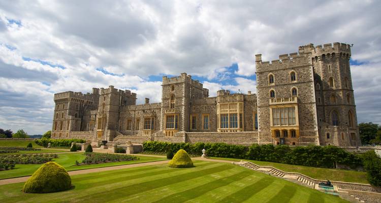 Expansive view of Windsor Castle’s long facade and manicured lawns under a partly cloudy sky.